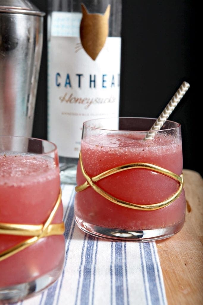 Two Strawberry Honeysuckle Sparklers sit on a wooden cutting board and blue-and-white striped dish towel