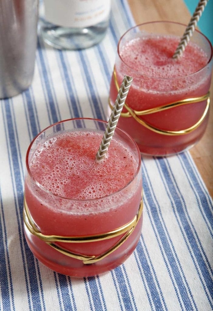 A close up of a glass cup on a plate, with Strawberry and Vodka