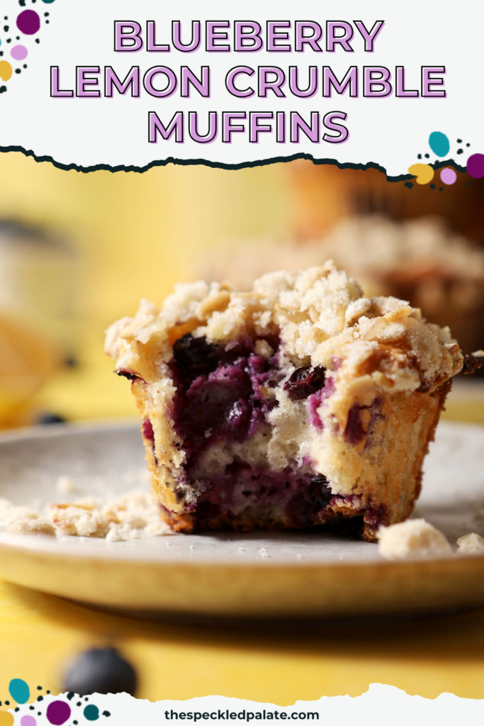Close up of a bitten-into blueberry lemon muffin with streusel on a grey plate on a yellow surface with the text blueberry lemon crumble muffins