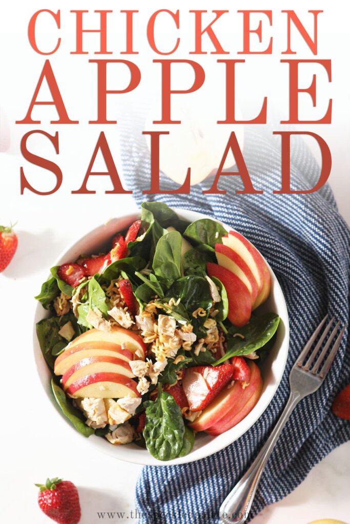 A bowl of chicken spinach salad on marble with the text 'chicken apple salad'