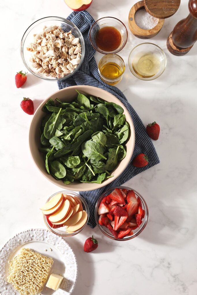 Ingredients for a spinach salad with chicken in bowls on marble