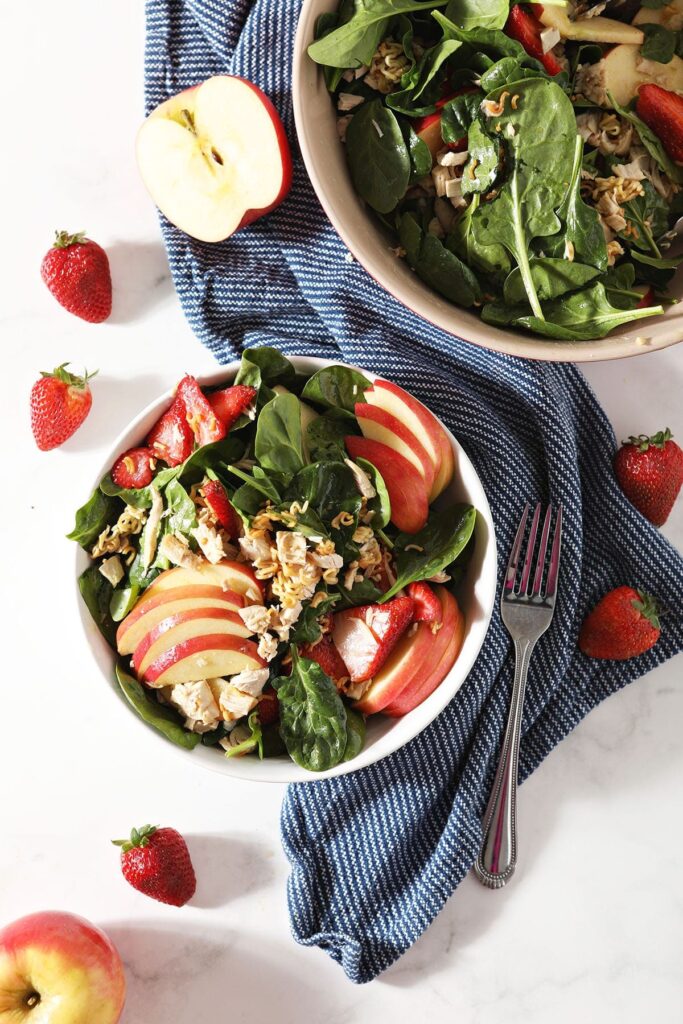 Two bowls of Chicken Spinach Salad with a blue napkin