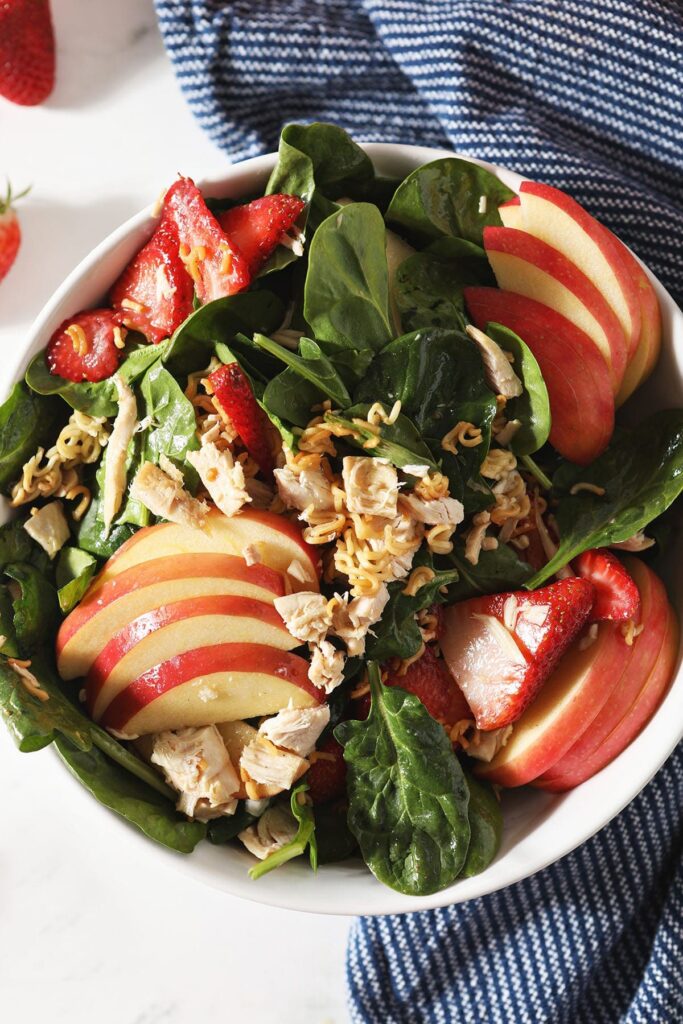 Apples, strawberries and chicken on a spinach salad