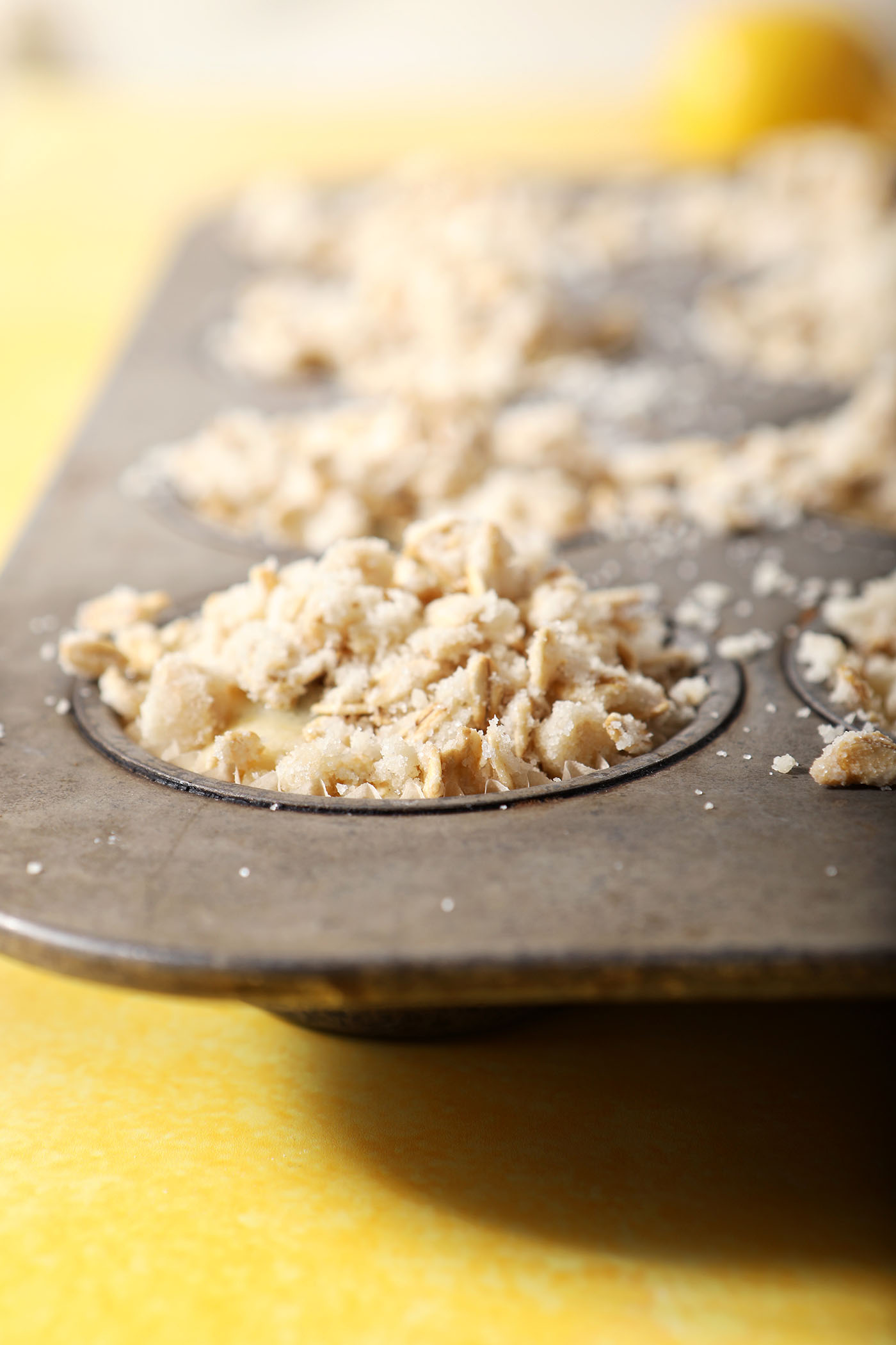 Blueberry lemon muffin batter topped with streusel in a muffin tin before baking