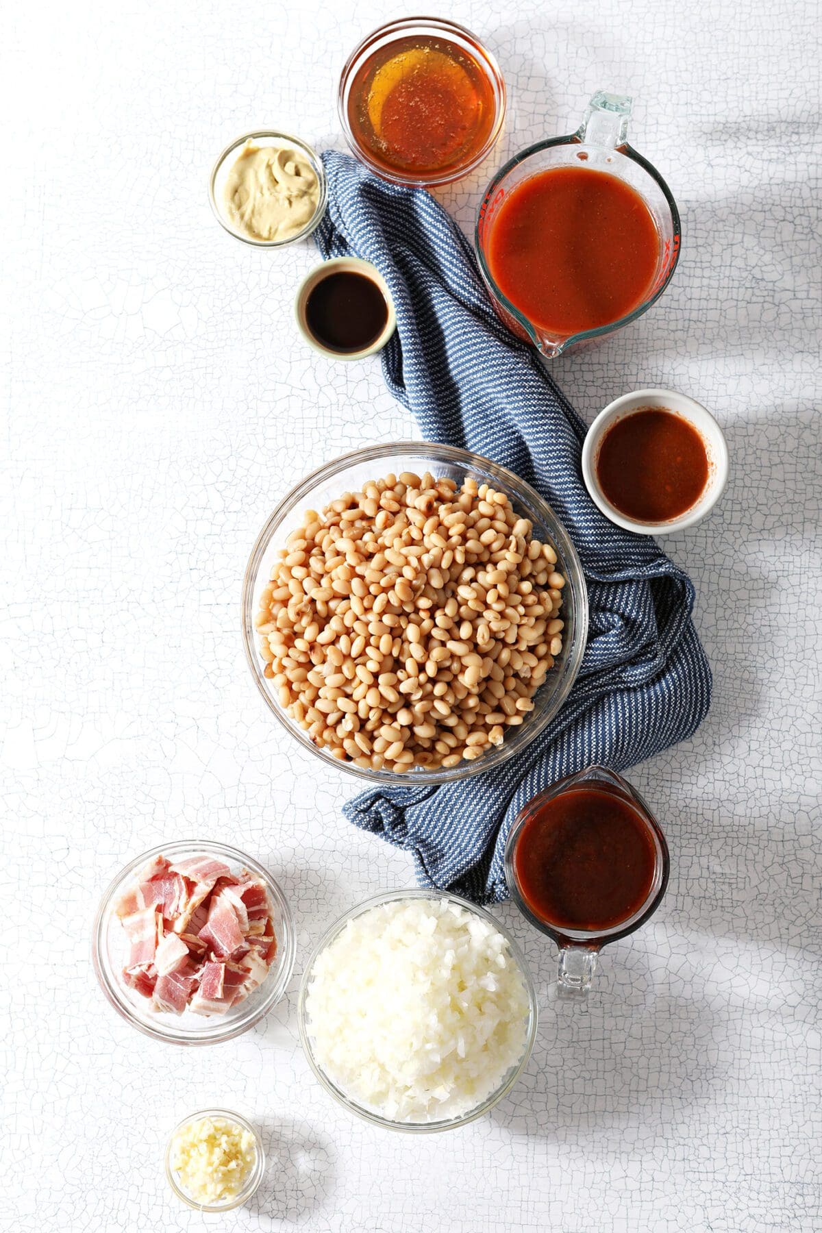 Bowls of beans and other ingredients on marble to make baked beans at home