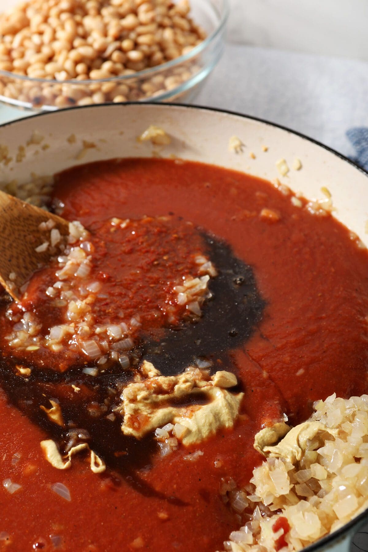 Sauce ingredients on top of the onions and garlic in a braiser pan