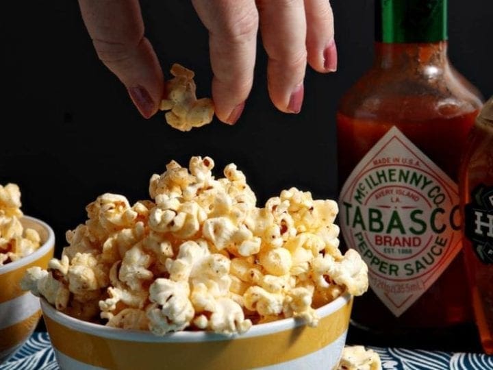 Hand picking up a piece of popcorn from a bowl filled with popcorn