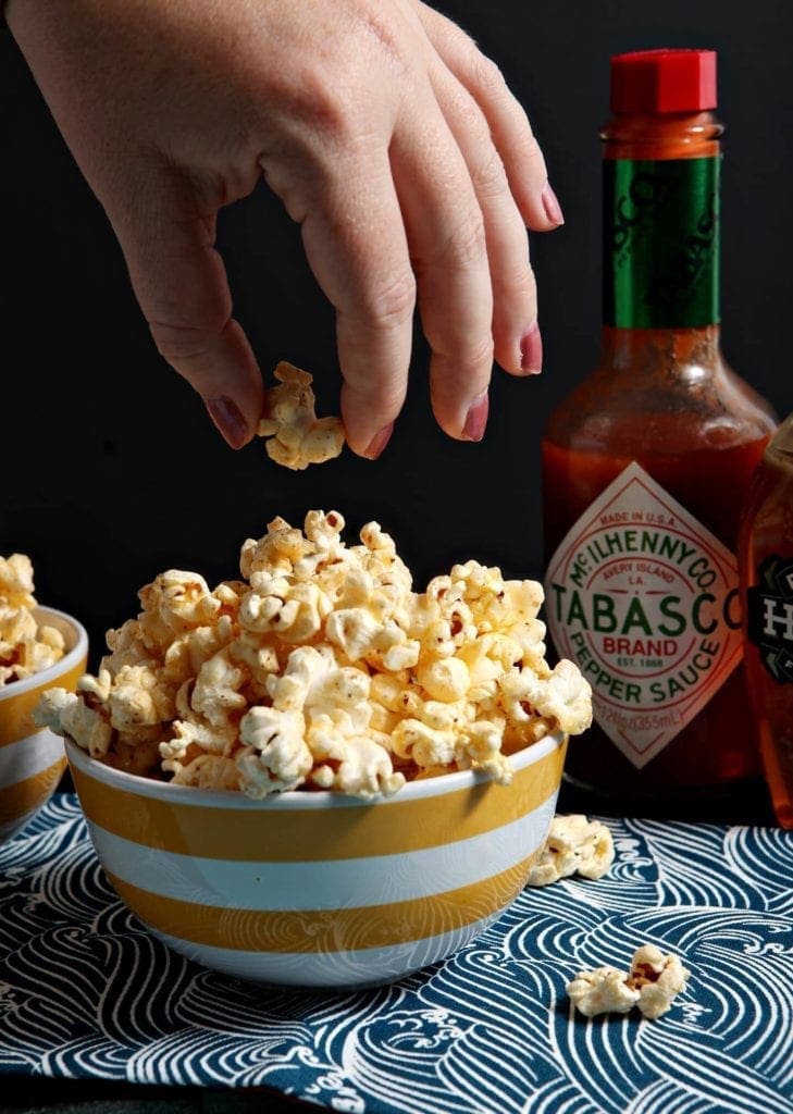 Hand picking up a piece of popcorn from a bowl filled with popcorn 