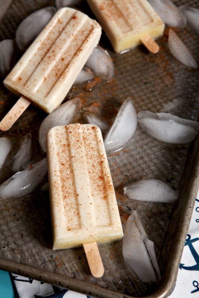 Three popsicles laying on tray of ice cubes 