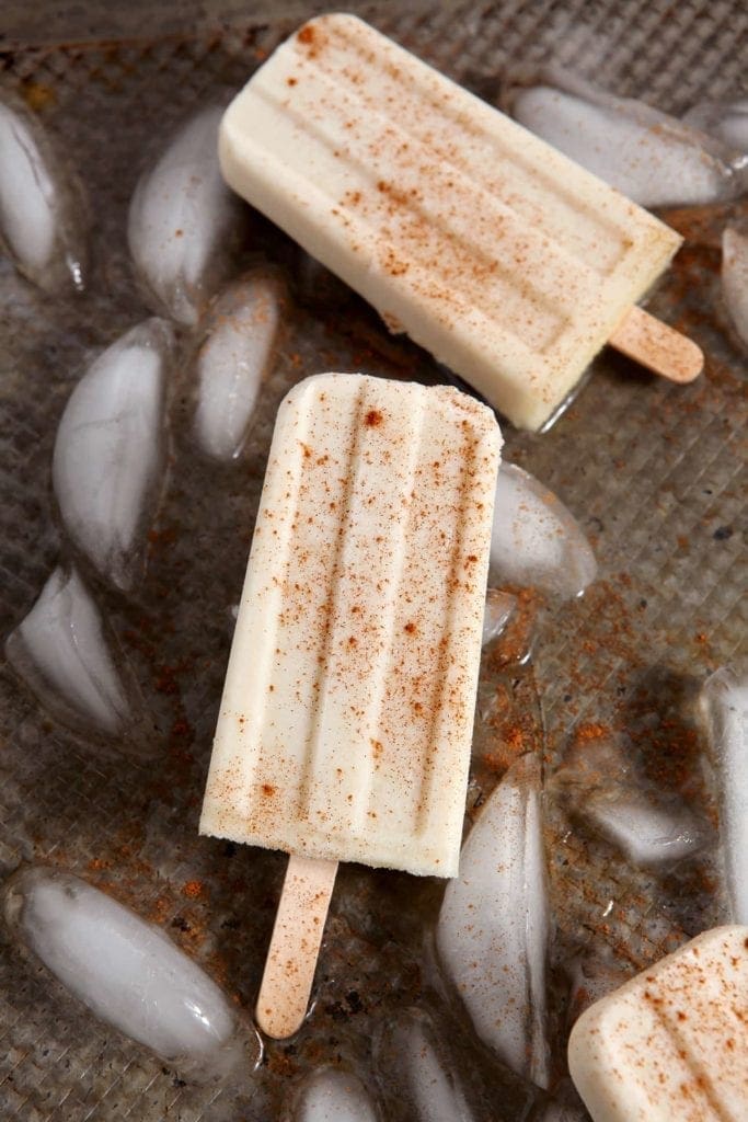 Popsicles laying on top of tray of ice cubes 