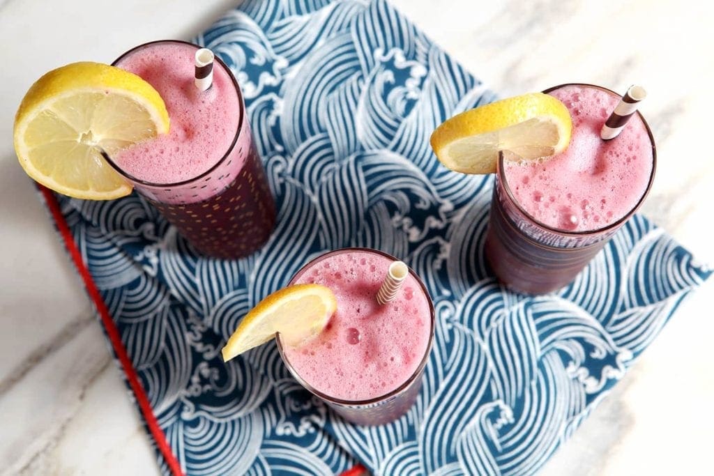 Three glasses of a blue frothy drink on a blue wave patterened napkin