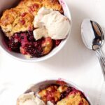 Two bowls of Blackberry cobbler with ice cream on top