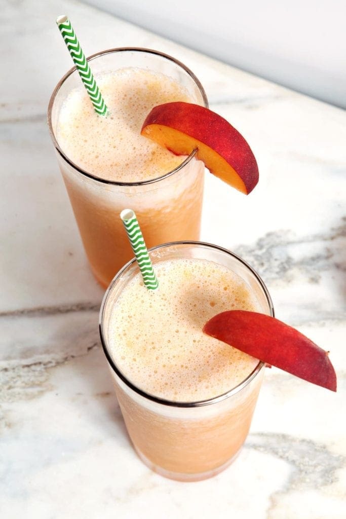 Overhead of two bourbon slushes with peach garnishes