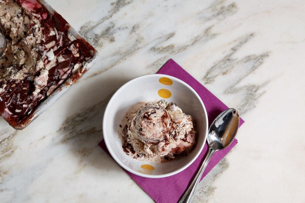 Overhead view of bowl of boozy stracciatella and raspberry gelato with spoon 