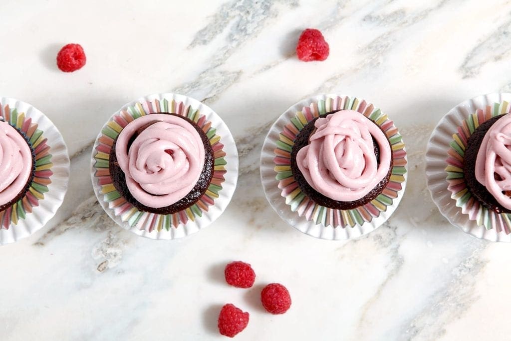 Overhead view of cupcakes with raspberries on table 