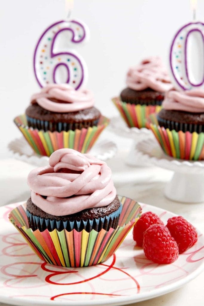 Close up of cupcakes in decorative wrappers with birthday number candles 