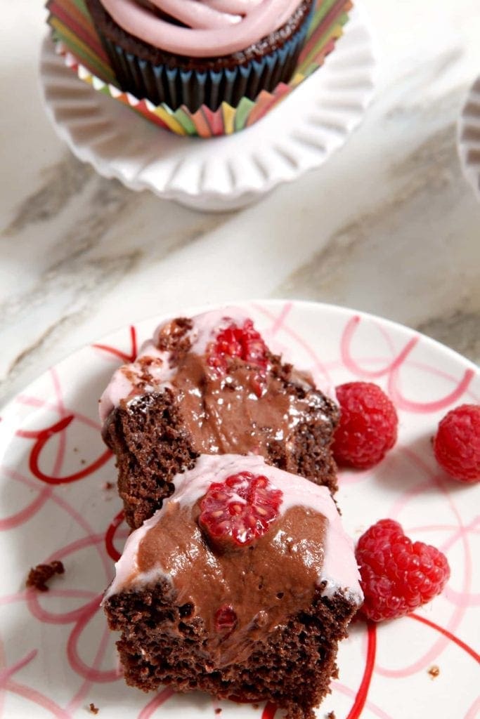 Close up view of inside sliced cupcake with raspberries on plate 