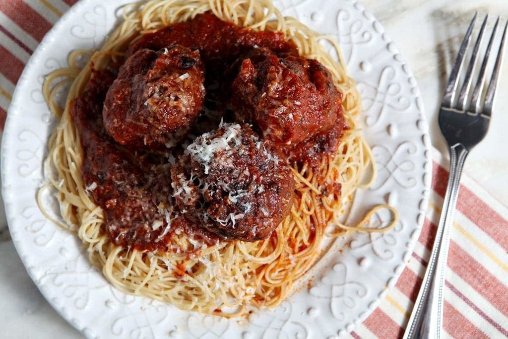 Overhead view of spaghetti and meatballs on white plate with fork 