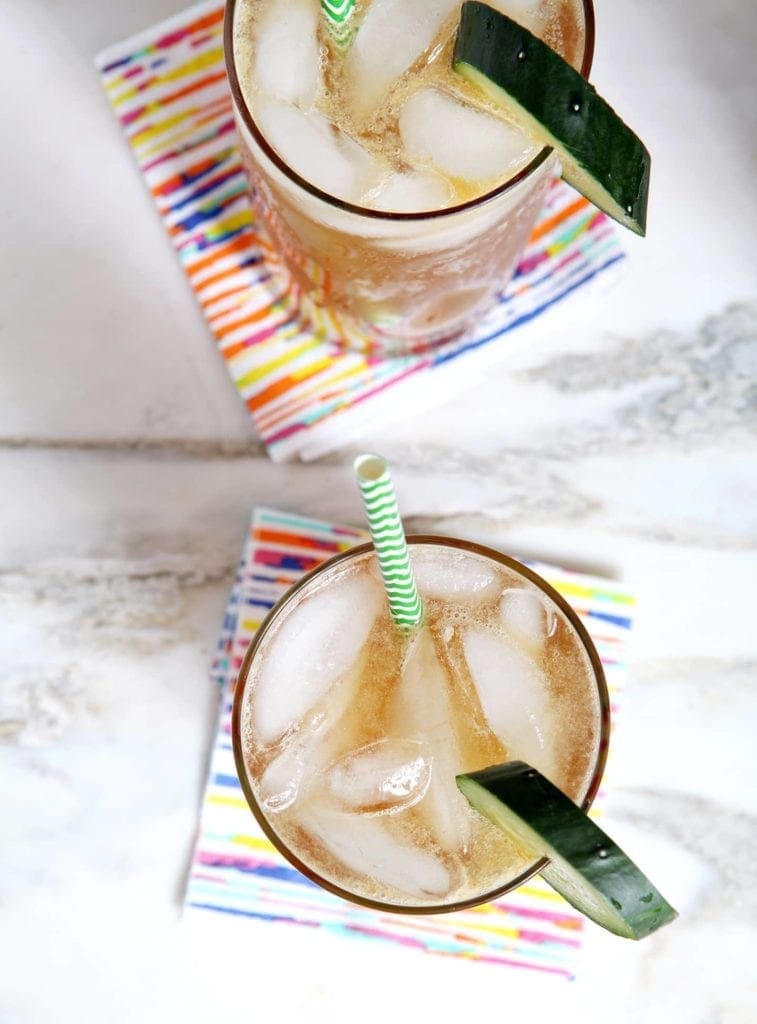 Two glasses of Pimm's Cups are seen from above, served with a slice of cucumber