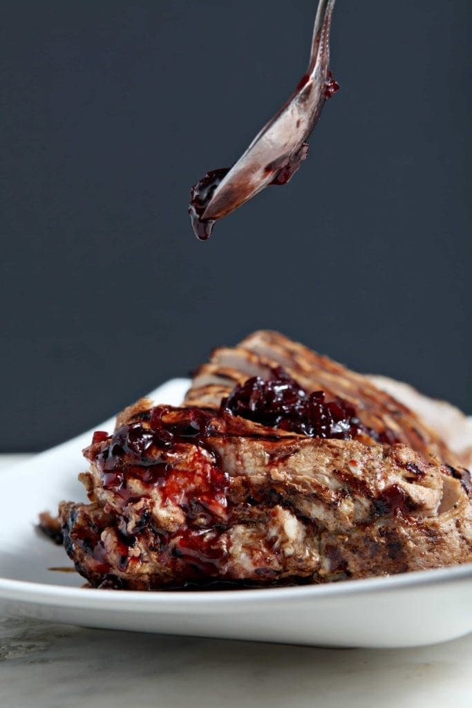 Spoon pouring sauce on top of pork tenderloin 