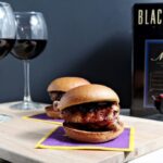 Two sliders in front of two glasses of wine and wine box