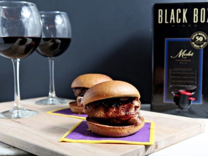 Two sliders in front of two glasses of wine and wine box