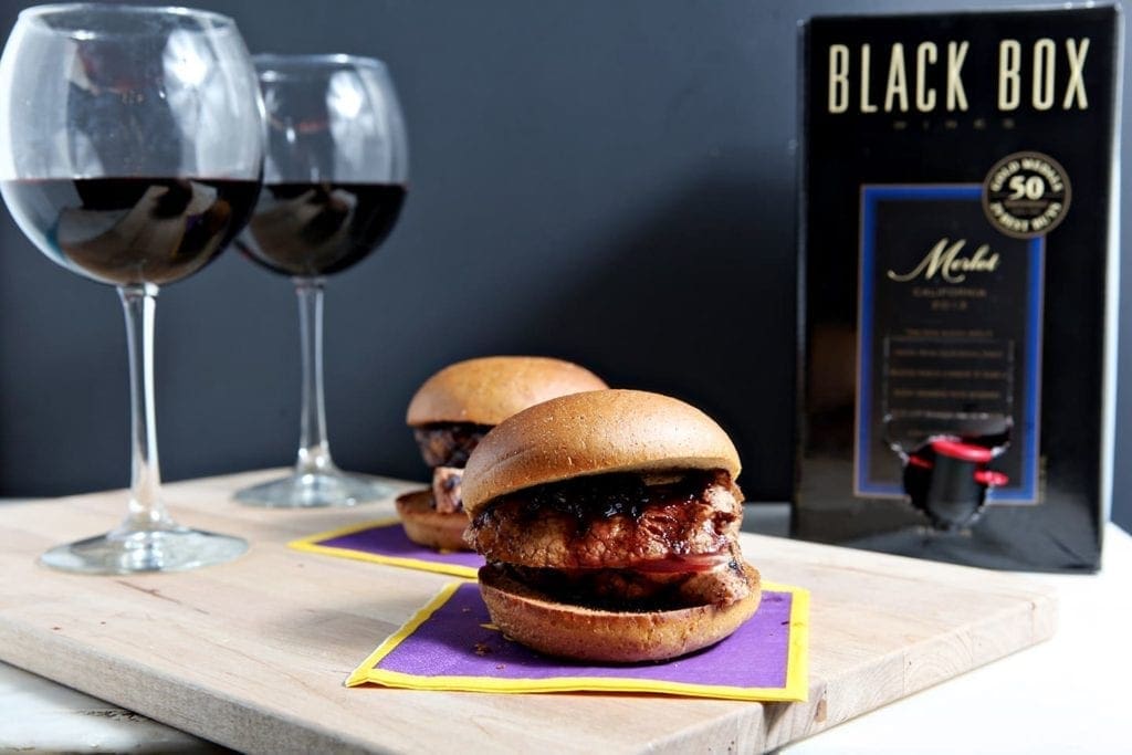 Two sliders in front of two glasses of wine and wine box 