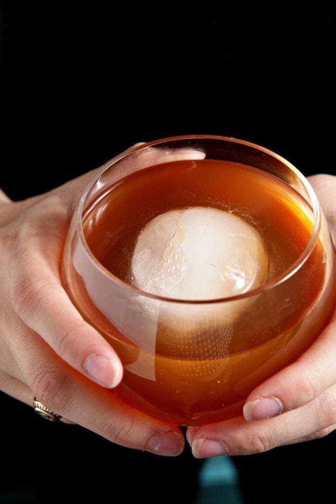 Overhead view of hands holding glass of african sunrise cocktail 