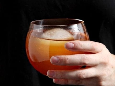 Hand holding glass of african sunrise cocktail