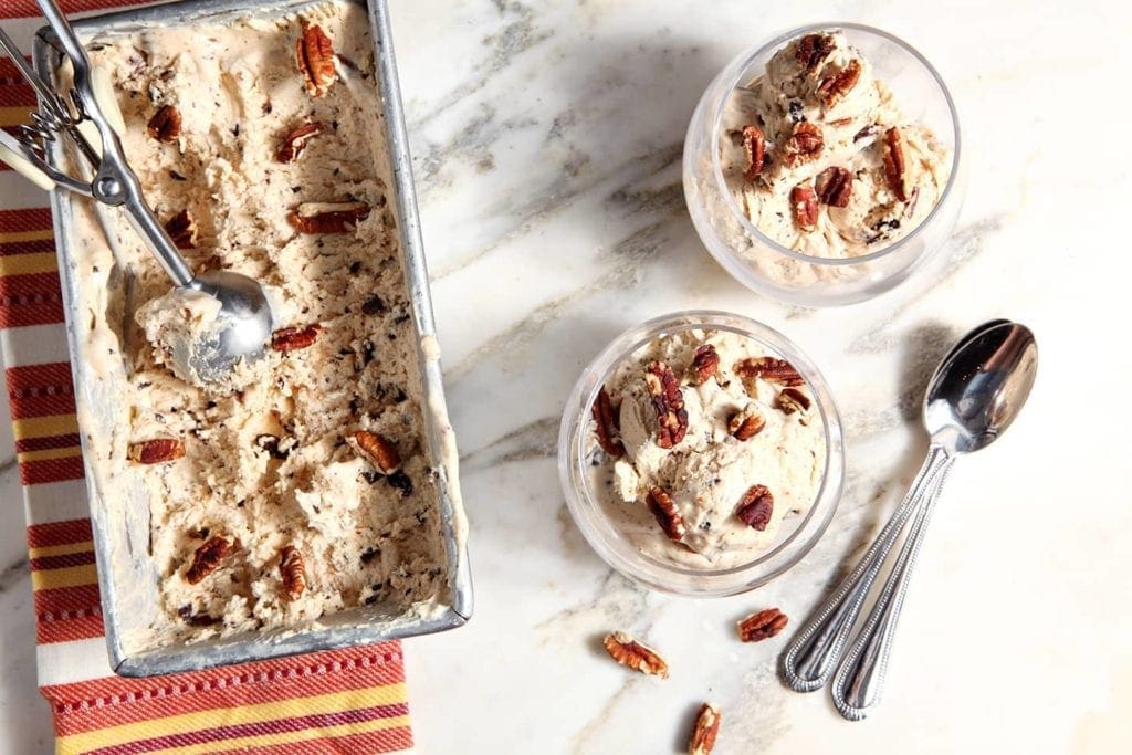 Two scoops of No Churn Peanut Butter Ice Cream in cups next to the pan of ice cream