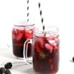 Two Blackberry Mint Spritzer sitting on a marble counter, iced and ready for drinking