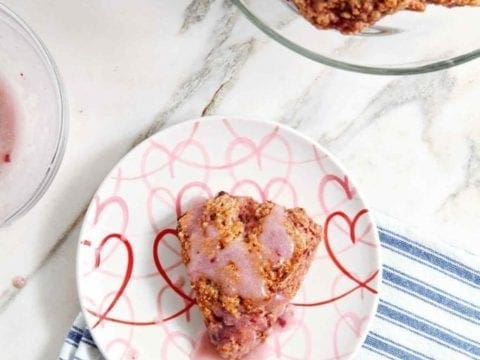 An iced Fresh Strawberry Scone sits on a plate before eating