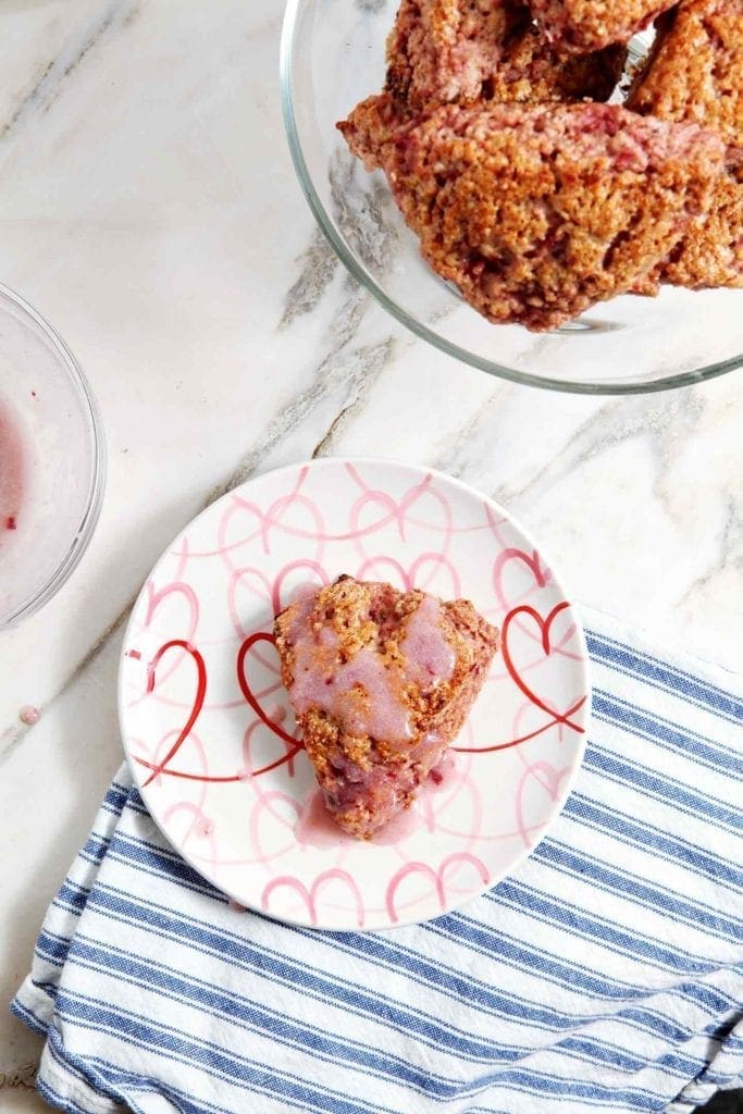 An iced Fresh Strawberry Scone sits on a plate before eating