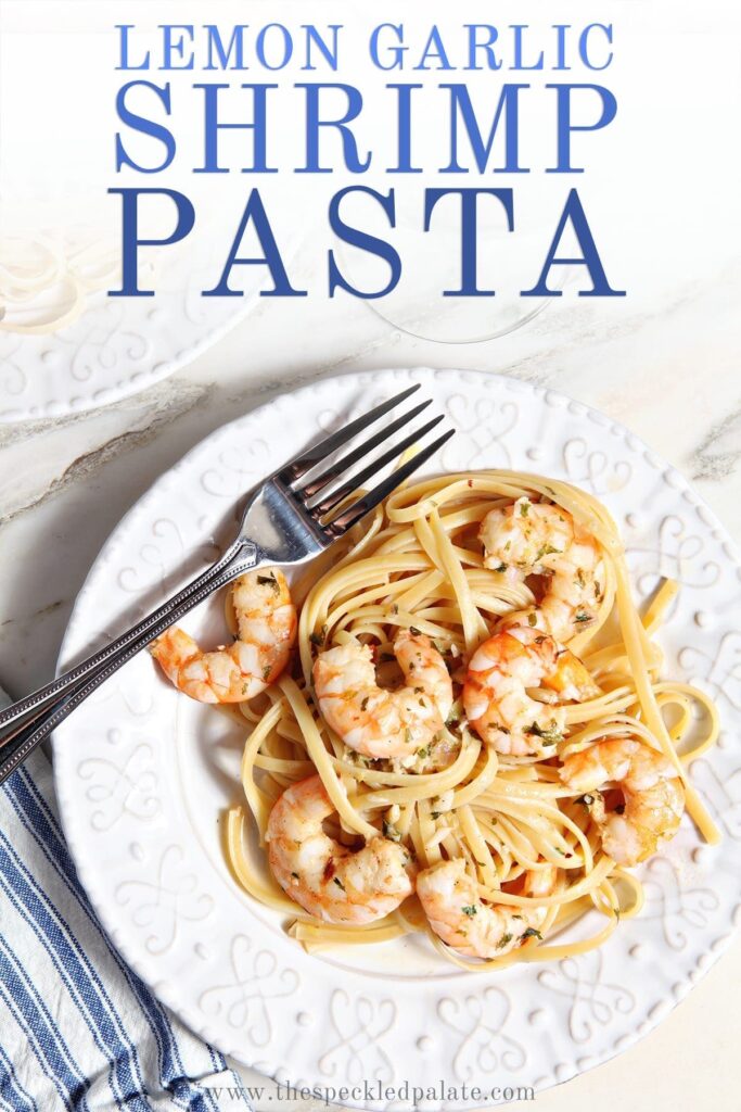 Lemon Shrimp Pasta on a white plate with a fork on marble with a glass of wine with the text 'lemon garlic shrimp pasta'