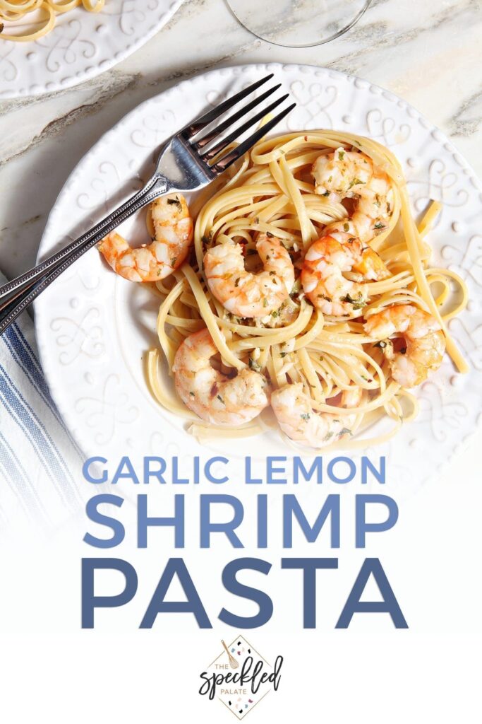 Lemon Shrimp Pasta on a white plate with a fork on marble with a glass of wine with the text 'garlic lemon shrimp pasta'