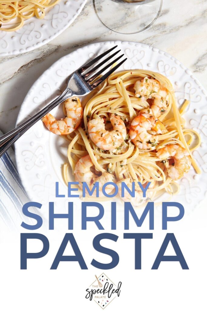 Lemon Shrimp Pasta on a white plate with a fork on marble with a glass of wine with the text 'lemony shrimp pasta'