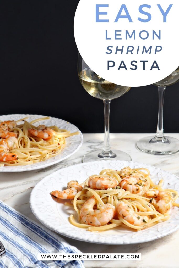 Two white plates hold Lemon Shrimp Pasta on marble with two forks and two glasses of white wine and the text 'easy lemon shrimp pasta'