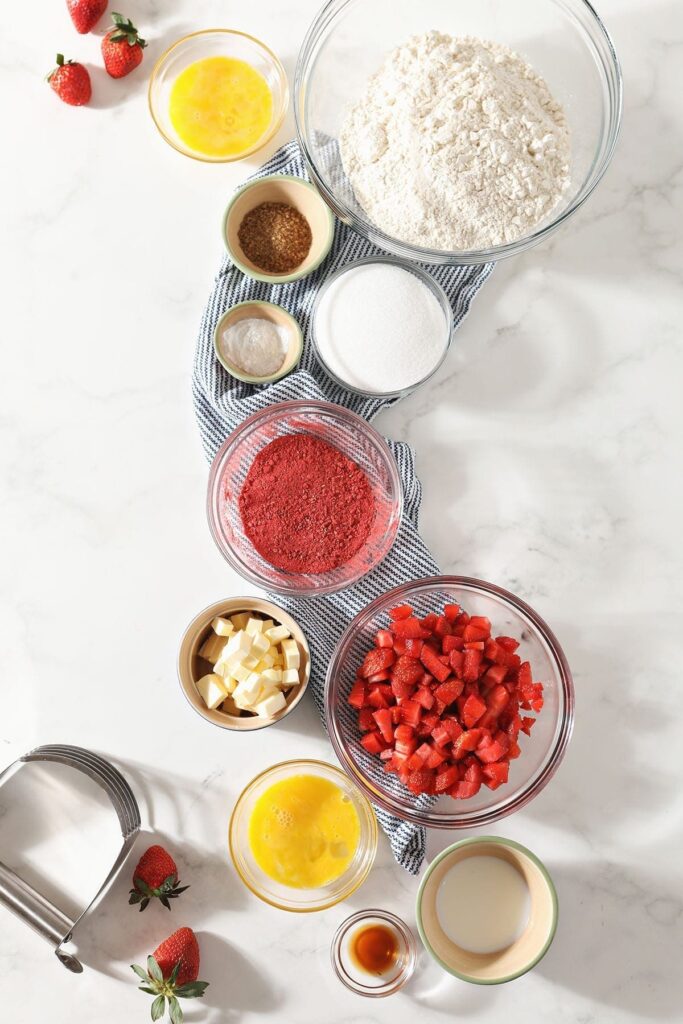 Ingredients for scones sit in bowls on a marble countertop with a blue striped towel