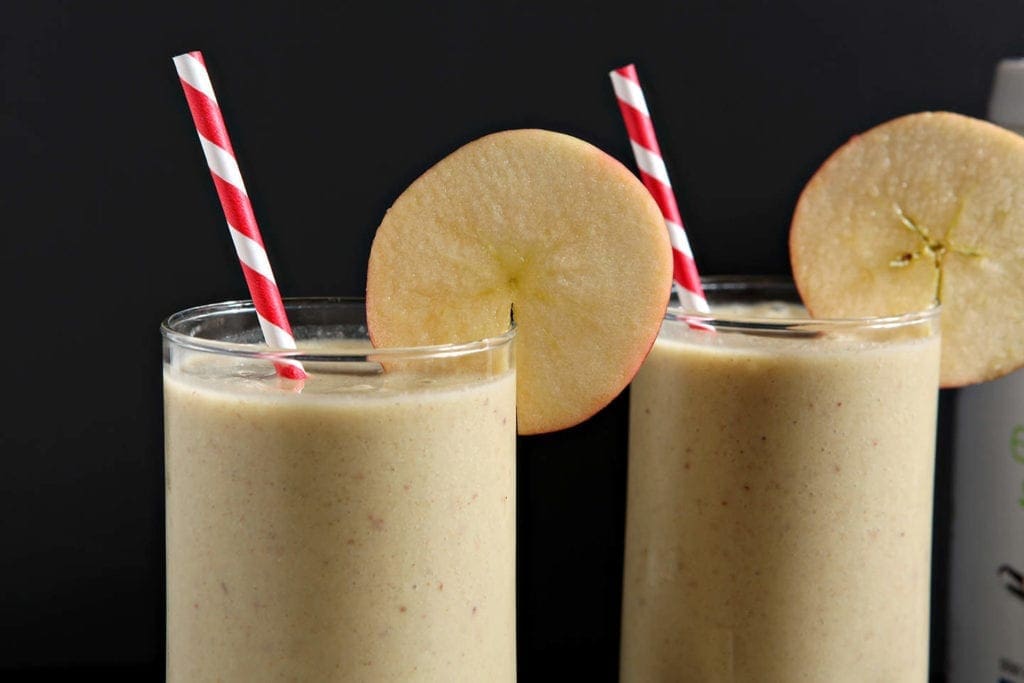 Close up of 2 glasses of smoothie with straw and garnish 