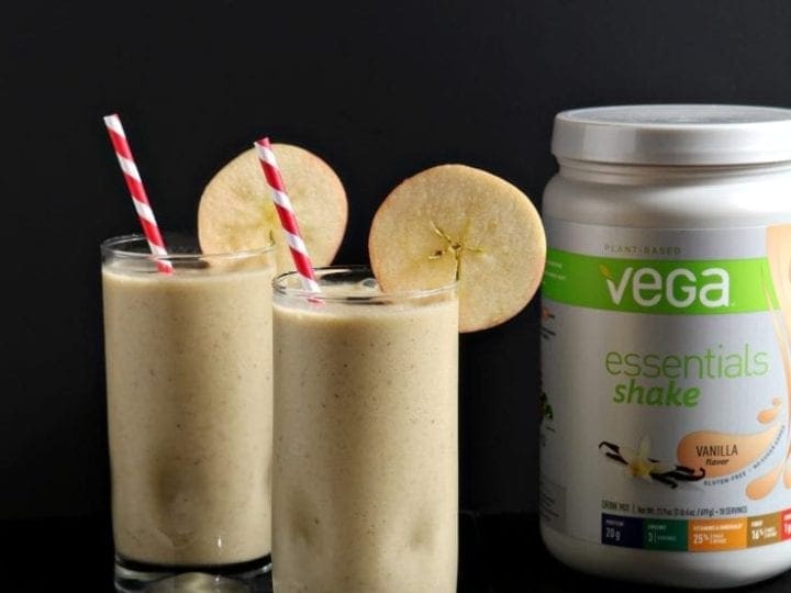 Two glasses of breakfast shake with straws and garnish next to shake container