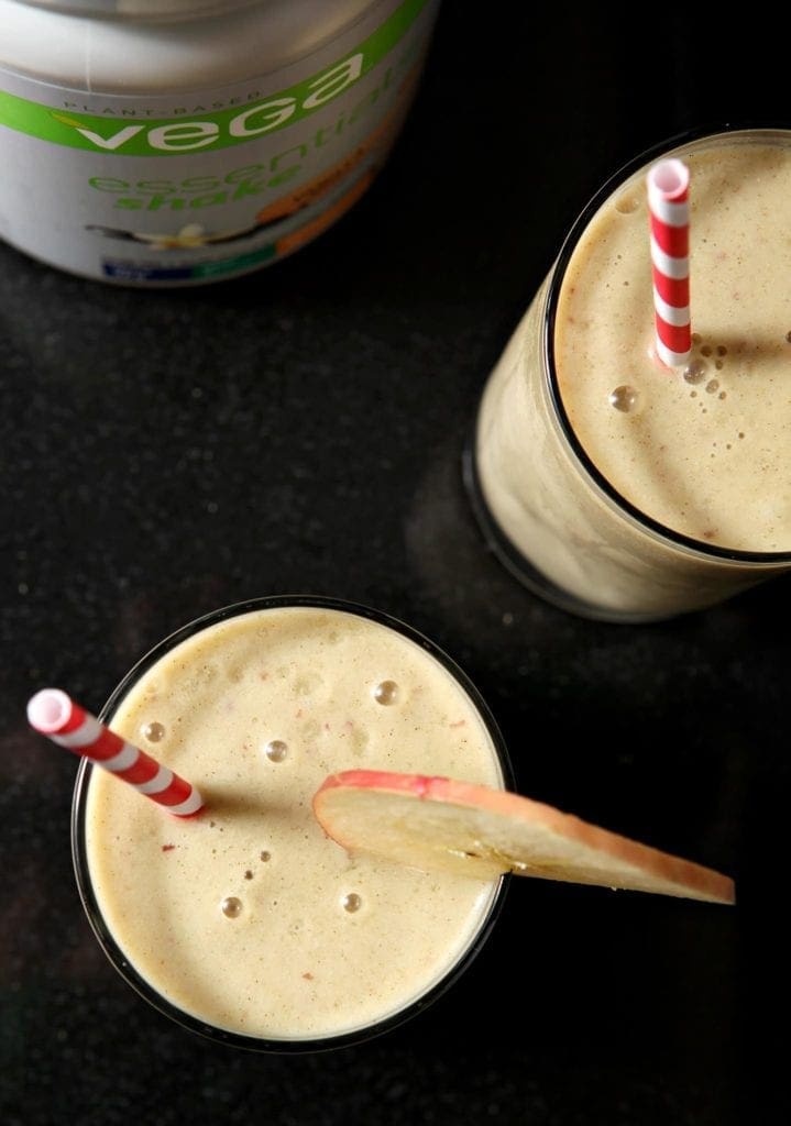 Overhead view of 2 smoothies in glasses with straw and apple slice garnish 