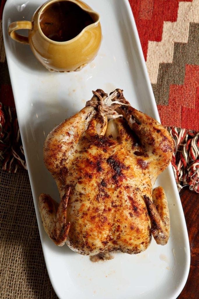 Overhead view of whole roasted turkey on white platter with yellow gravy boat 