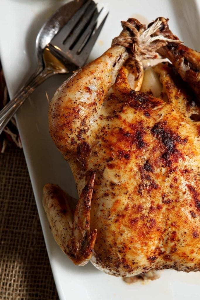 Close up of whole roasted turkey on platter with with fork and spoon 