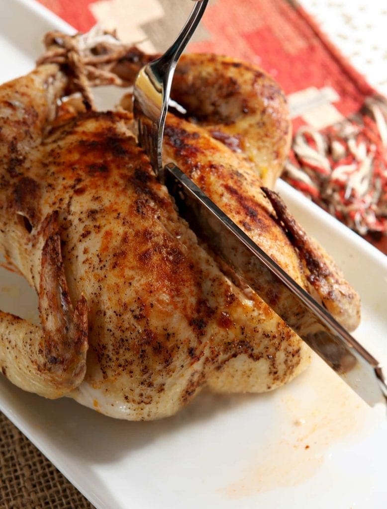 Knife and fork cutting into whole roasted turkey 