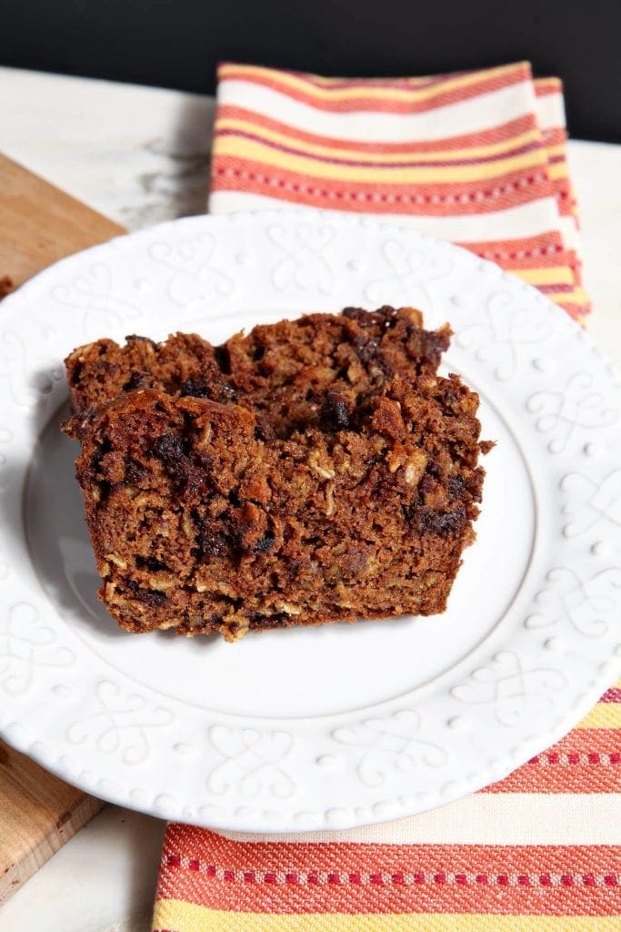 Two slices of Gluten Free Pumpkin Bread with Chocolate Chips on a white plate on top of a striped orange towel