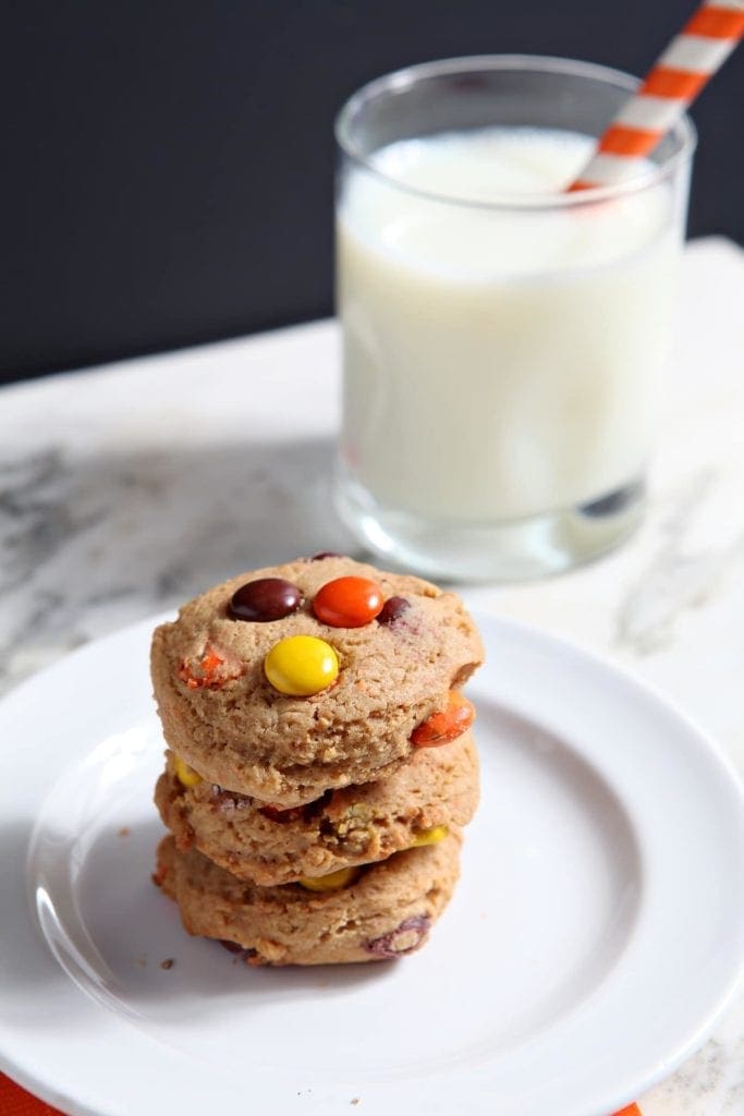 Close up of 3 stacked cookies on white plate with glass of milk 