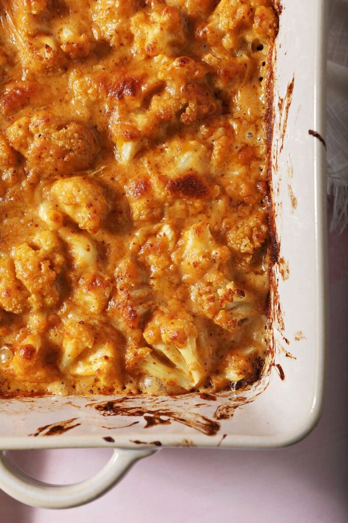 Close up of cheesy cauliflower in a white casserole dish