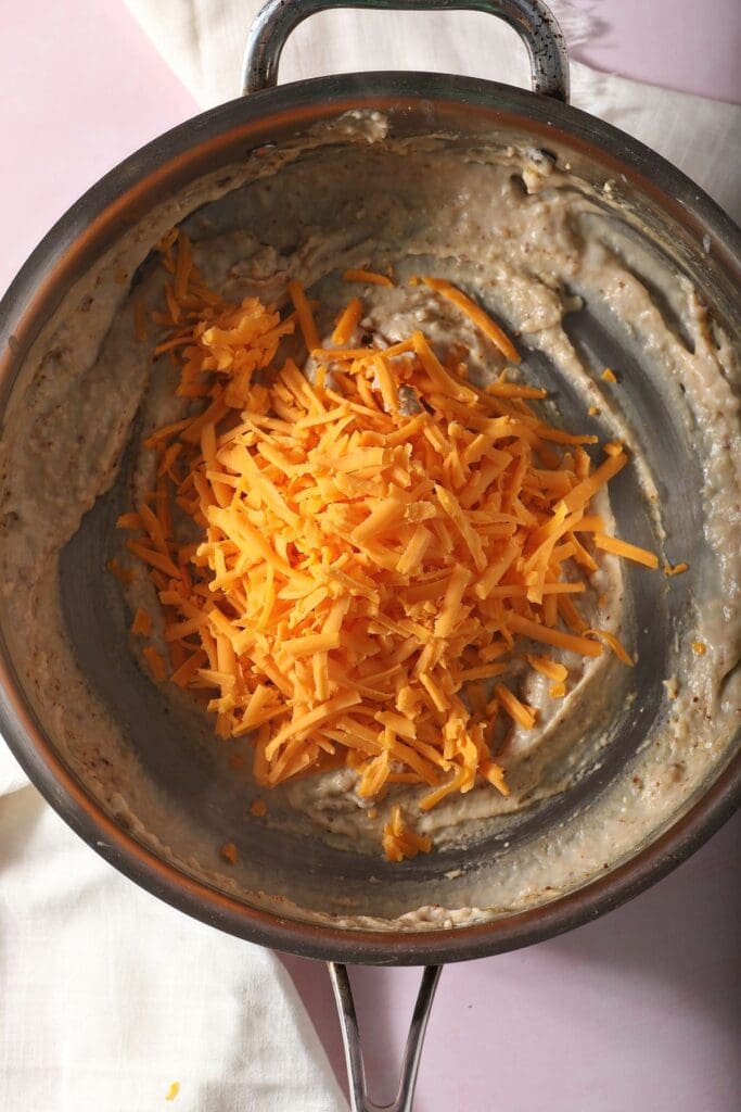 Shredded cheese on top of the ingredients to make a cheese sauce