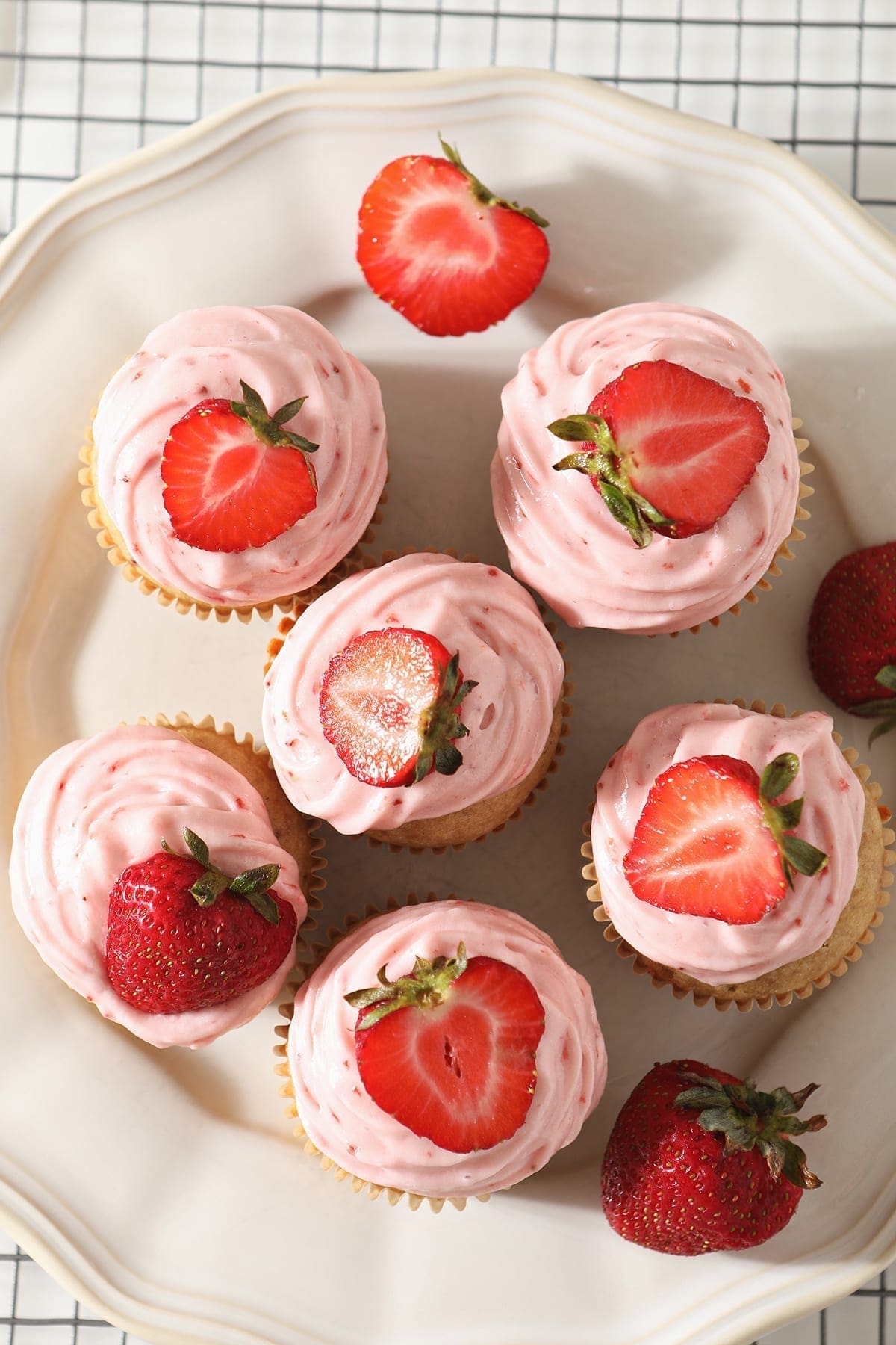 Overhead of a white platter holding six decorated Strawberry Cupcakes