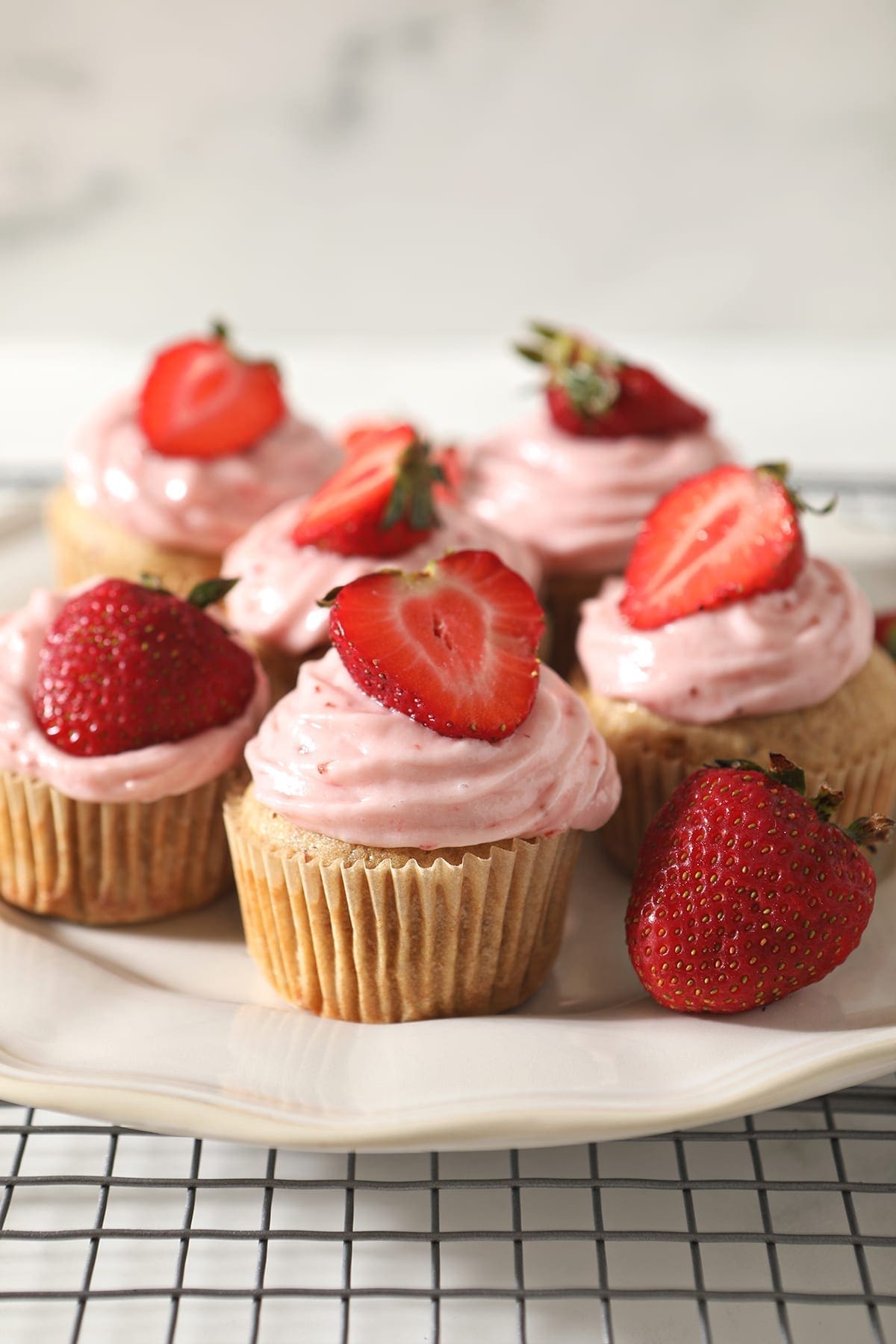 A white platter of decorated Strawberry Cupcakes